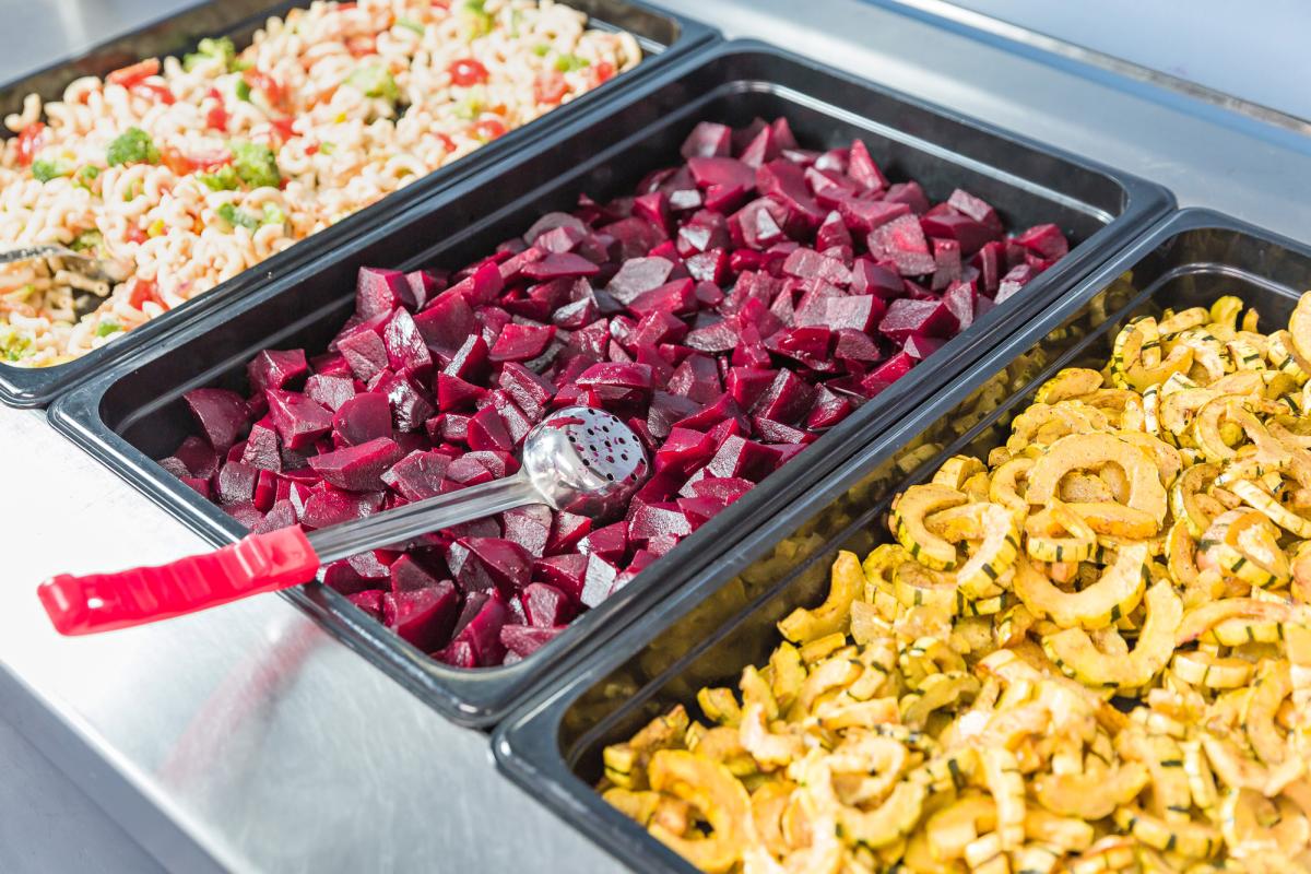 A lunch bar filled with beets, pasta salad, and baked squash.