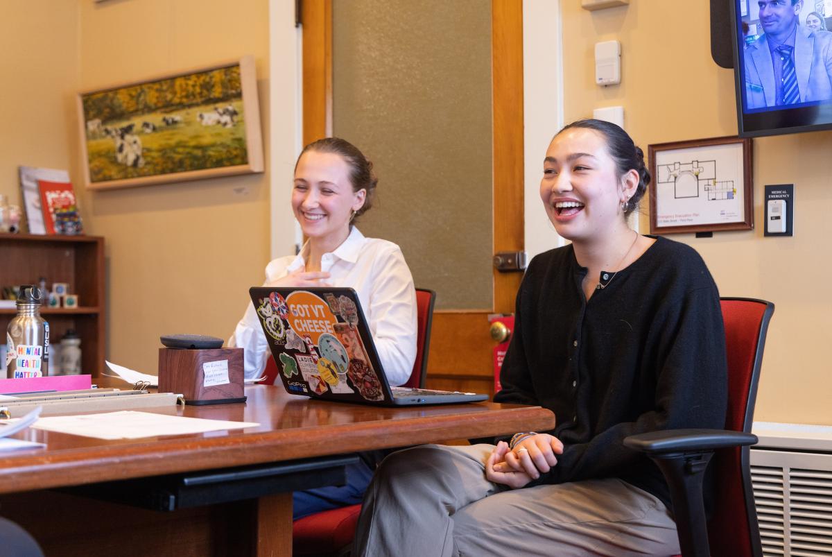 Two students are sitting at a conference table in the state house, engaged in discussion.