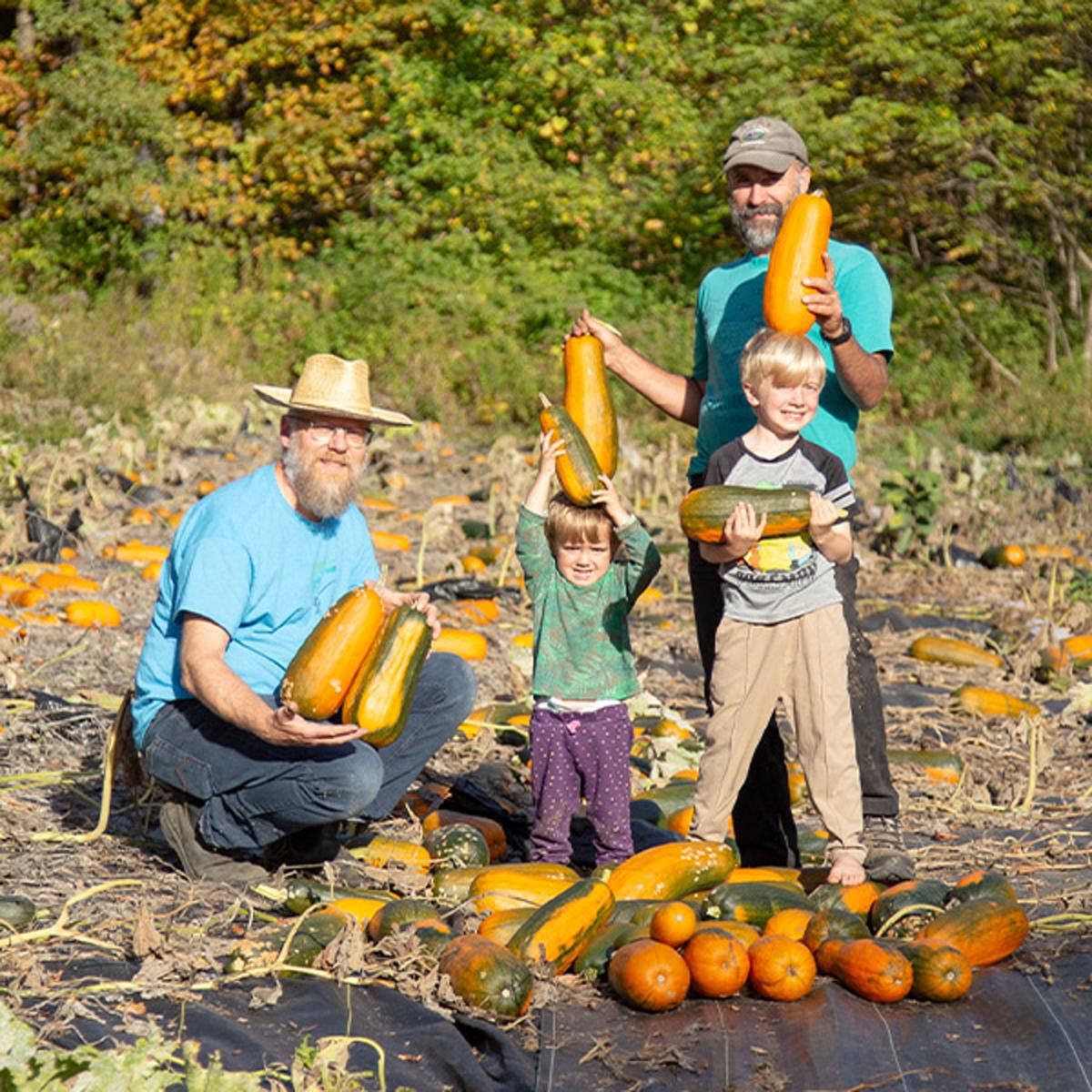 Two adults and two children in a squash patch.