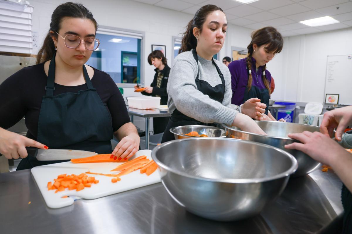 Students prepare carrots in an education kitchen. Students prepare carrots in an education kitchen.