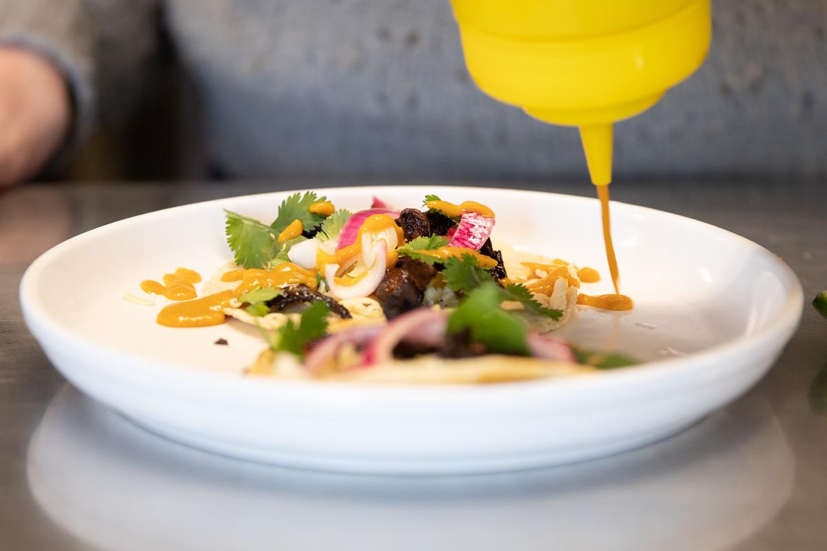 hot sauce being poured on top of a taco hot sauce being poured on top of a taco