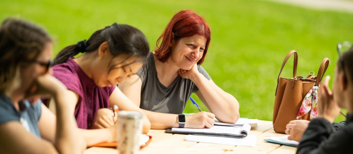 educators sit at an outdoor picnic table, deep in discussion educators sit at an outdoor picnic table, deep in discussion