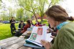 A farmer looks over a farm to school resource book outdoors at a picnic table during a workshop.