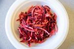 a bowl of magenta root slaw with shredded carrots, beets, and parsnip