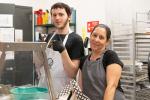 a student and teacher smile as they work in the cafeteria kitchen